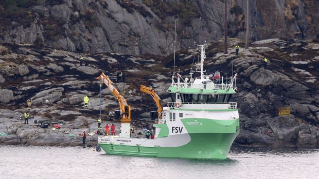 A recovery vessel lifts up parts of the crashed helicopter off the island of Turoey, near Bergen, Norway (AP)