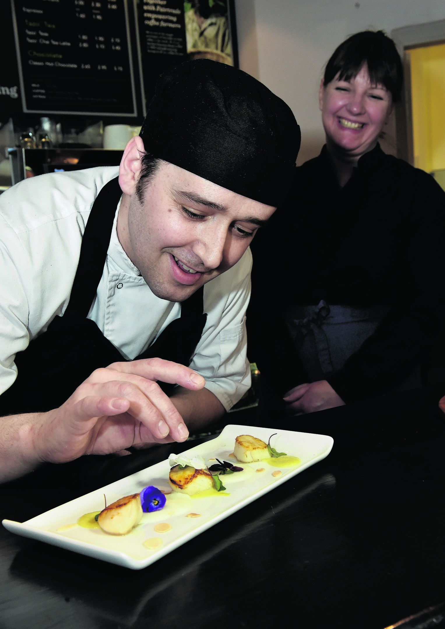 Restaurant reveiw - The Porterhouse Restaurant - Thainstone Centre, Inverurie. Chef Greig Rose prepares the Saint-Jacques Scallops served with a celery veloute scuce, pineapple foam and toasted flaked almonds. Waitress Trudi Munro in the background. Picture by COLIN RENNIE April 19, 2016.