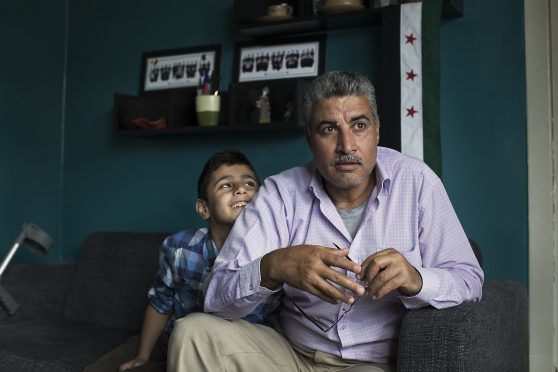 Thamer Al-Johmani sits at home as his youngest son Omar cuddles his father.