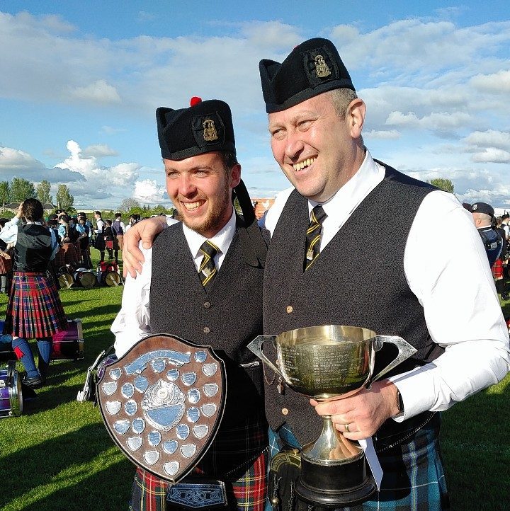 Lead Drummer Cameron McClure and Pipe Major Scott Taylor, of the City of Inverness Pipe Band collect their trophies
