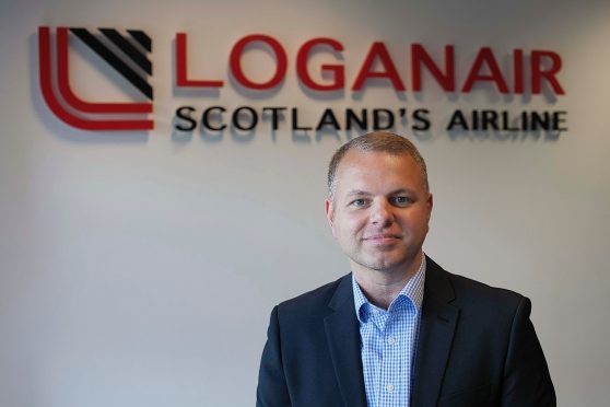 Loganair CEO Jonathan Hinkles in front of the airline's logo.