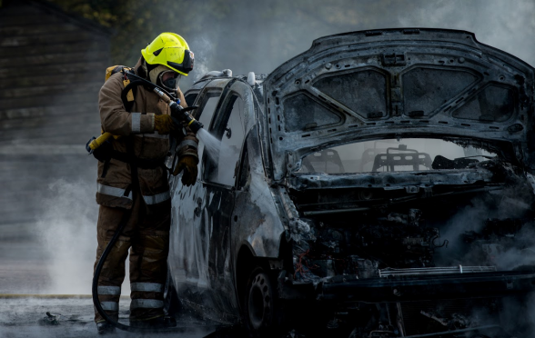 A firefighter damps down the burnt out car in Fort William