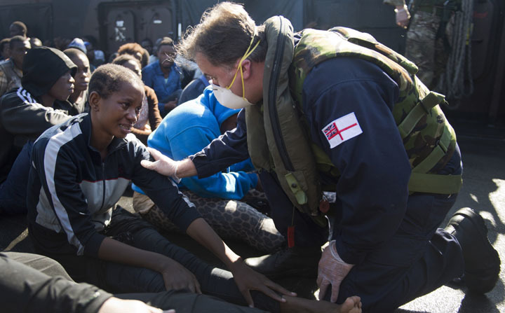 Best Professional Image In Show: Sub Lieutenant Ruairi Holohan RNR, helps some migrants picked up by HMS Bulwark’s LCU onto the ship. L(Phot) Jay Allen