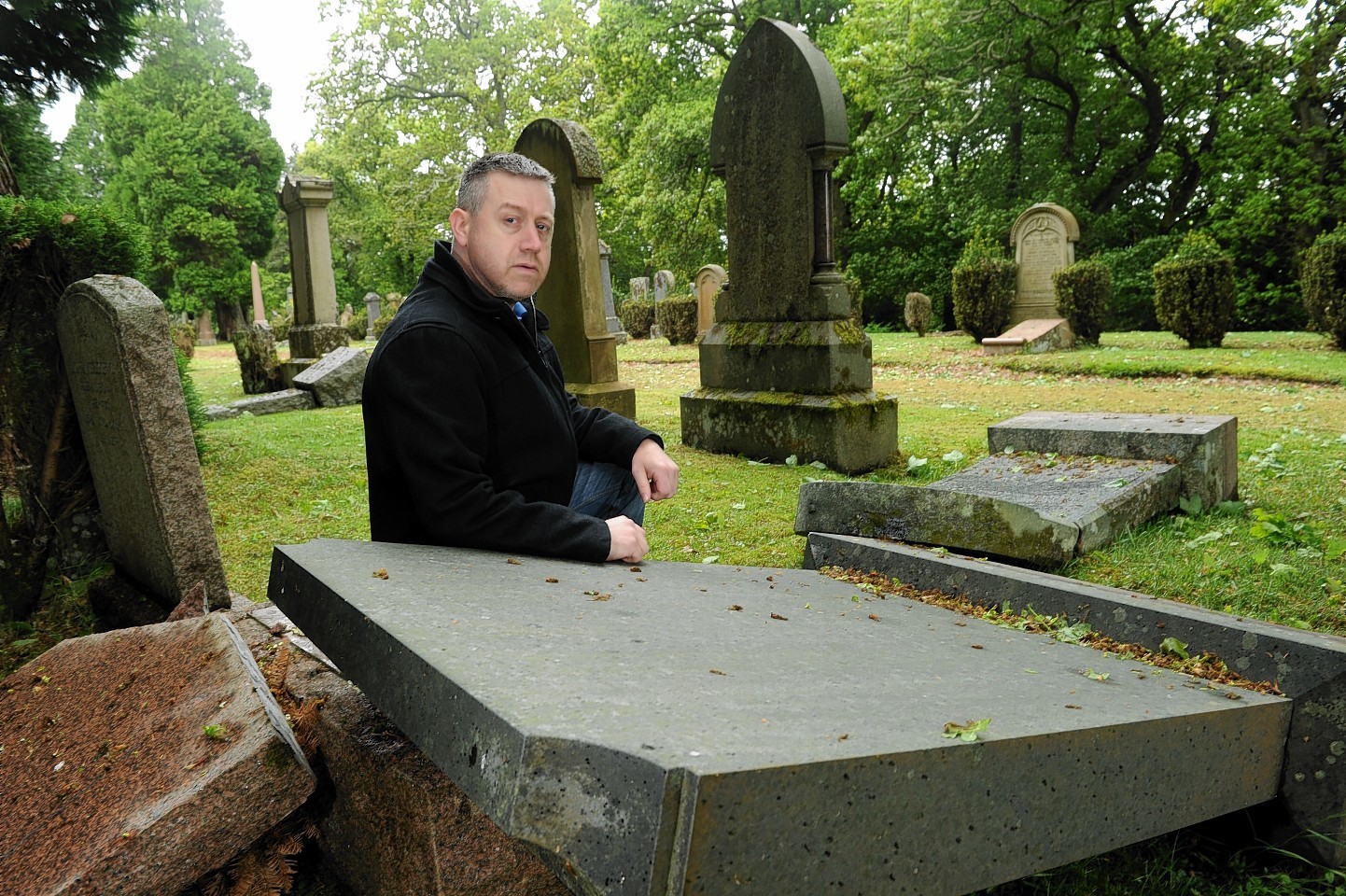 Allan Duffy next to one of the ruined gravestones