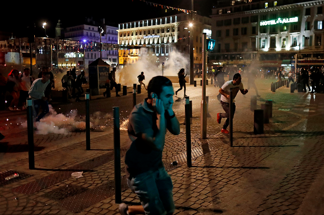 People run after police fired tear gas following clashes after the Euro 2016 soccer championship group B match between England and Russia in Marseille, France