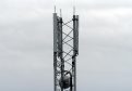 The top of a mobile phone mast with grey clouds in the background.