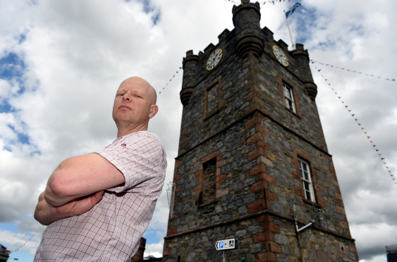 Dufftown business owner Alistair Jeffs next to the clock tower in the town, which will be dwarfed by the proposed electric poles.
