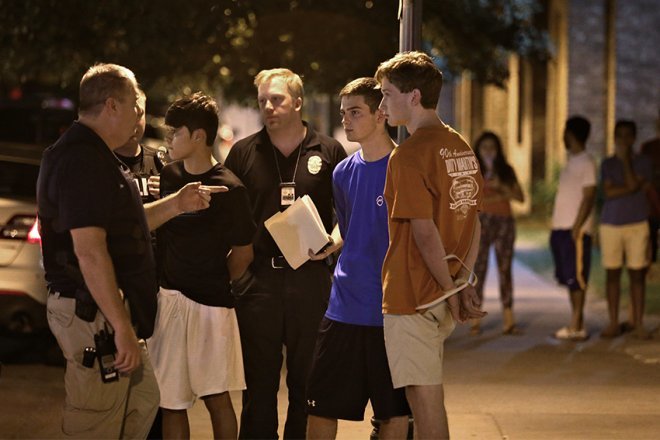 Daniel Hamilton Magee, in blue, stands with Austin Police Department officers after being arrested. Photo Credit: Daulton Venglar