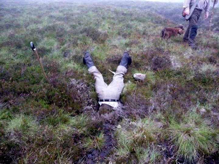 Gamekeeper Jonny Stevenson with head down hole. See Centre Press story CPHOLE; These dramatic pictures show a brave gamekeeper climbing head first into an underground pipe to rescue a dog who went missing on an Angus moor. Cocker spaniel Jazz disappeared while picking up game during a grouse shoot at the Invermark Estate on Tuesday. She was eventually found down a muddy open pipe on the moor. Gamekeepers dug through 6ft of wet peat to retrieve her Jonny Stevenson pushed himself down the pipe to check on the spaniel's condition.