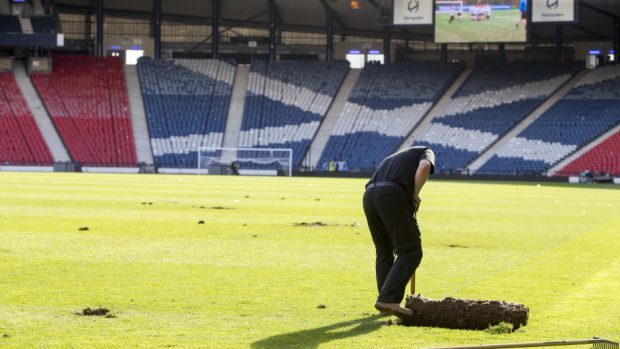Hampden Park ground staff clean up after the pitch invasion at the end of the Scottish Cup final
