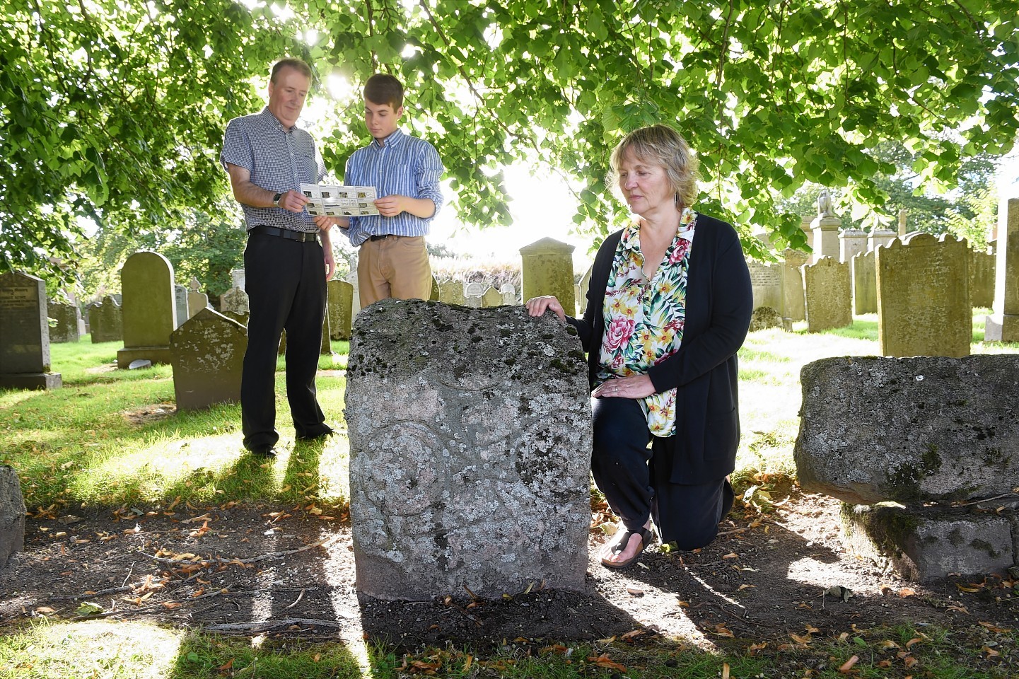 Community councillors Mike Hebenton and Josh MacRae and local resident Elizabeth Barrow with the Pictish Symbol stones at Inverurie Cemetery