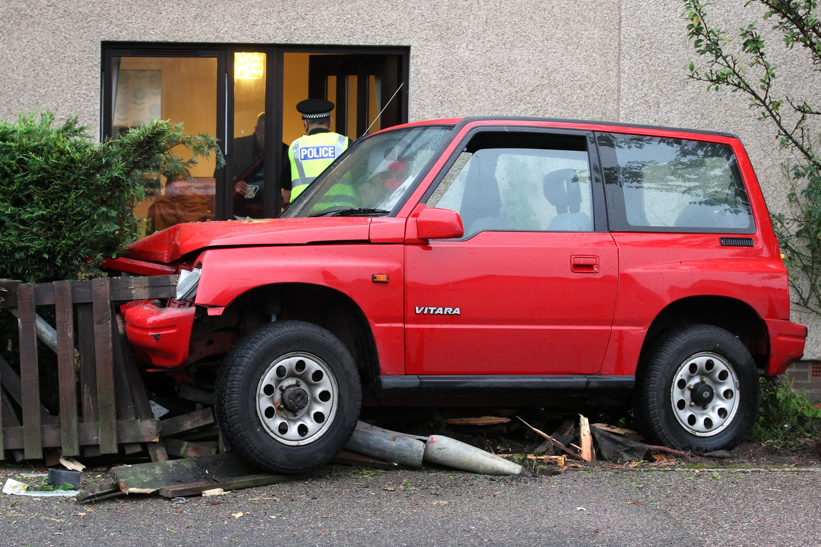 The red Suziki Vitara crashed through the fence of a residential property and came to a halt in the garden, destroying a lamp post in the process.