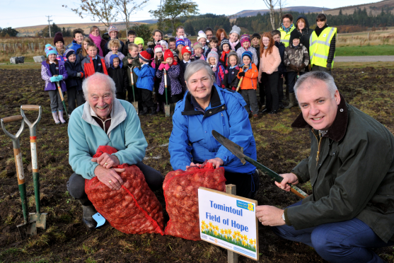 Planting daffodils in the new Tomintoul Field of Hope. Mike and Des Budd  with Richard Lochhead, MSP, front, and pupils of Tomintoul Primary School, who are helping to plant the bulbs, back. Picture by Gordon Lennox.