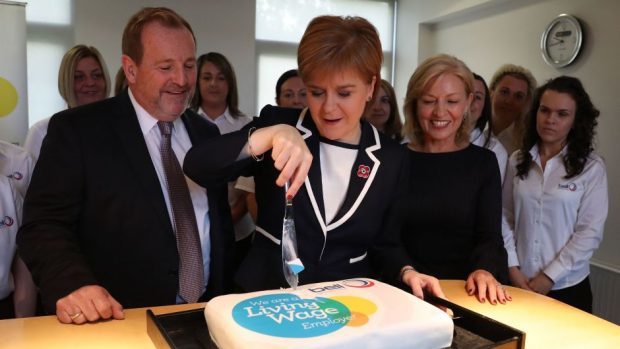 First Minister Nicola Sturgeon cuts a cake to mark an increase in the living wage