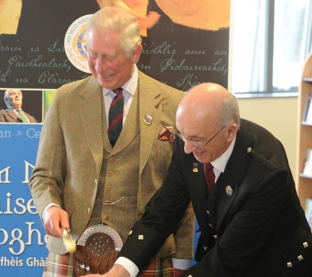 Prince Charles cuts a commemorative cake to mark 125th anniversary of An Comunn Gaidhealach accompanied by John Macleod, President of An Comunn Gaidhealach in the Nicolson Institute.