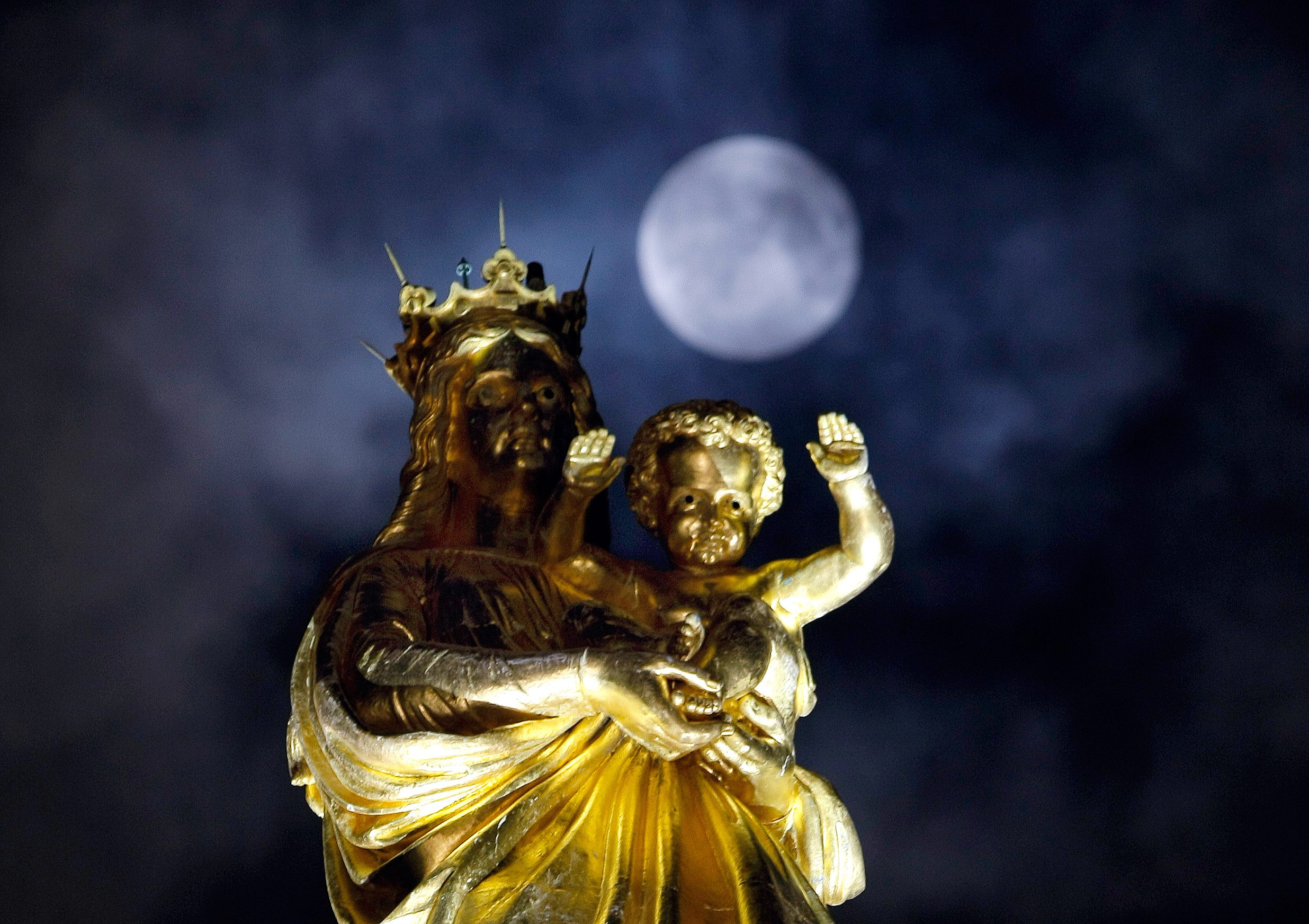 A super moon pasts behind a statue of the Virgin Mary and the Child at Notre Dame de La Garde basilica, before a total lunar eclipse, in Marseille, southern France, Monday, Sept.28, 2015. (AP Photo/Claude Paris)