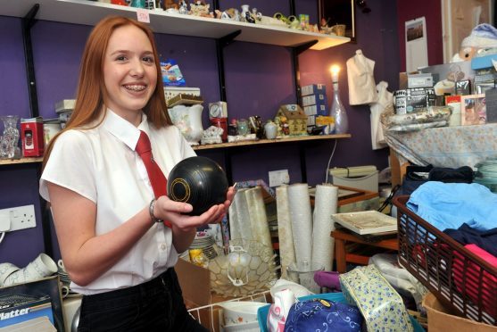 Eilidh Angus, in the charity shop she's running in Queen Street, Lossiemouth to help fund her trip to Mongolia, with a selection of items which have been donated for sale, including a set of lawn bowls. Picture by Gordon Lennox.