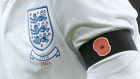 Detail of an England player wearing a black armband with a poppy symbol on aside the England badge