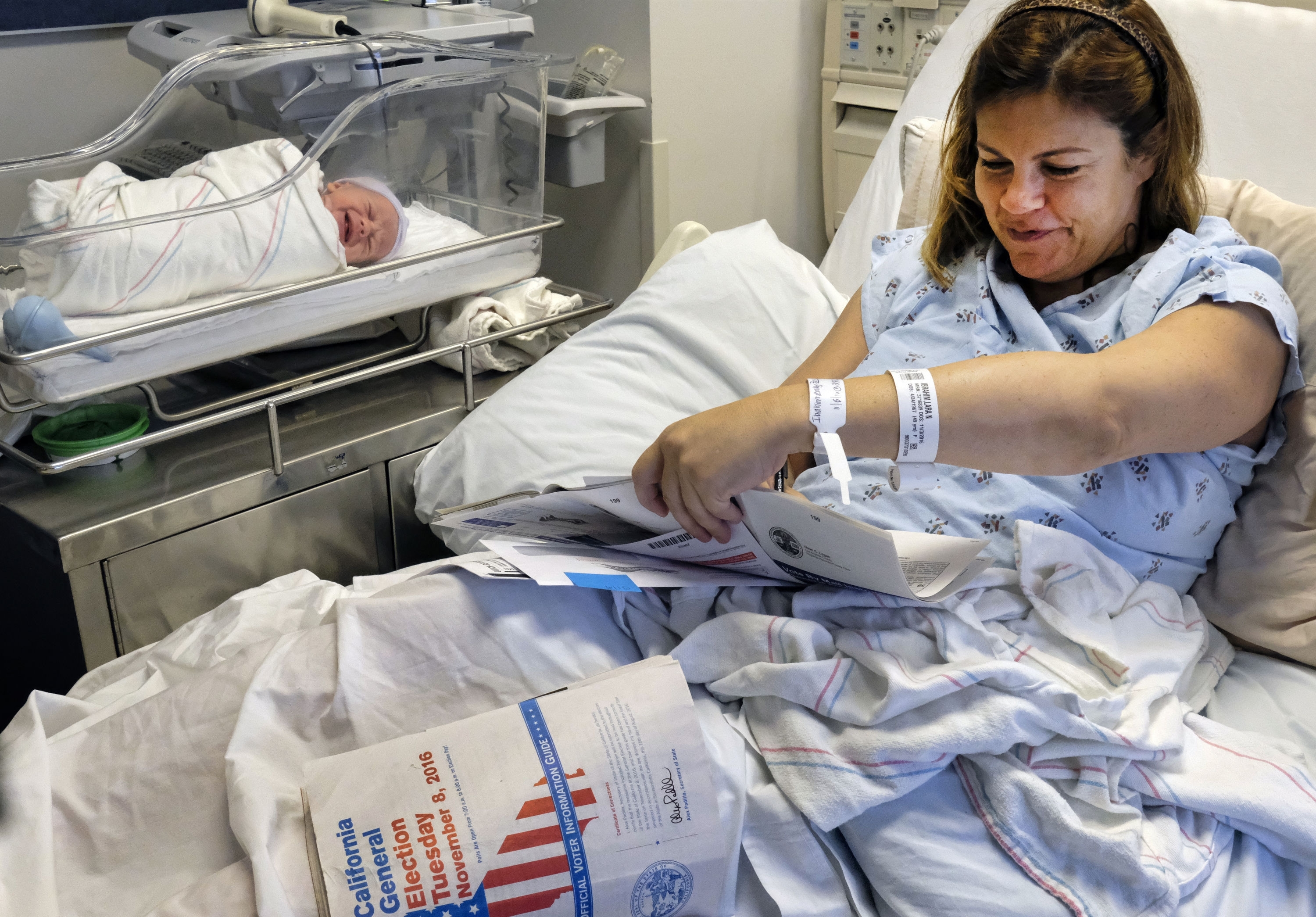 With her newborn son George by her side, Lara Ibrahim fills out her election ballot from her hospital bed at the Ronald Reagan UCLA Medical Center in Los Angeles on Tuesday, Nov. 8, 2016. Dozens of patients at the hospital were able to vote from their beds thanks to a volunteer program. Ibrahim had planned to vote at her usual polling place but ended up giving birth earlier than expected. (AP Photo/Richard Vogel)