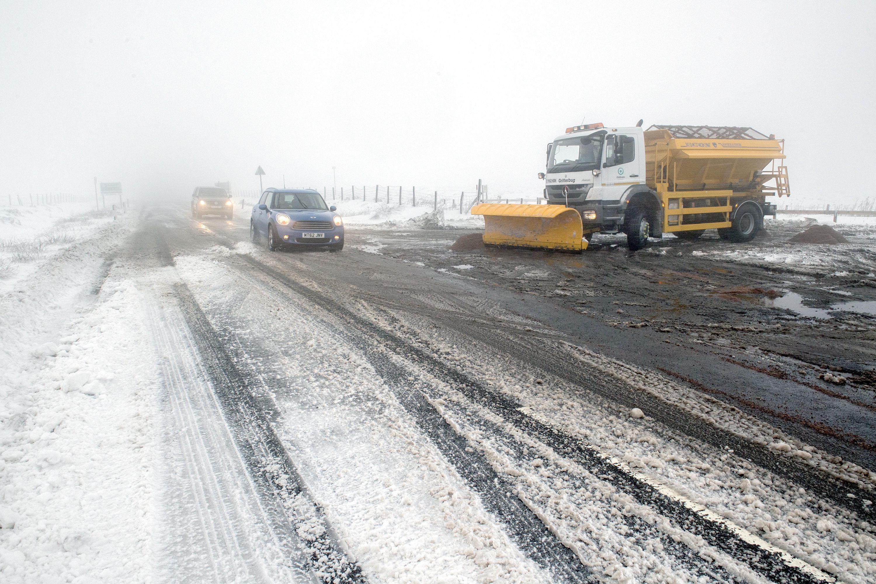 Cars pass a snow plough on the A635 in Saddleworth Moor