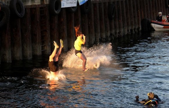 Swimmers run off the quayside at Burghead before swimming back to dry land.