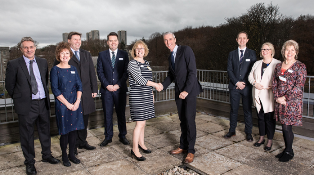 NHS Grampian project director Jackie Bremner and GRAHAM Construction regional director Gary Holmes shake on the deal - surrounded by senior colleagues from their organisations