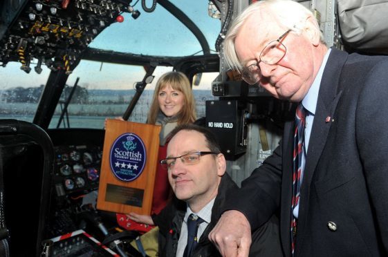 Jo Robinson, Visit Scotland, in the captain's seat of Morayvia's star attraction, the Sea King helicopter, holding the four star award she presented to the aviation centre, with Mark Mair, centre, chairman of Morayvia, and Lord Lieutenant of Moray, Grenville Johnston, right.