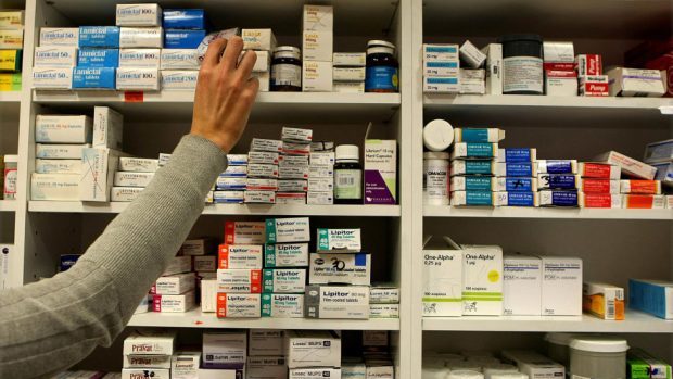 A pharmacist reaches for a box of tablets