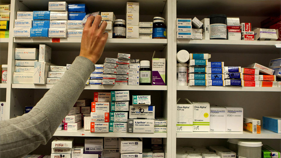 A pharmacist reaches for a box of tablets