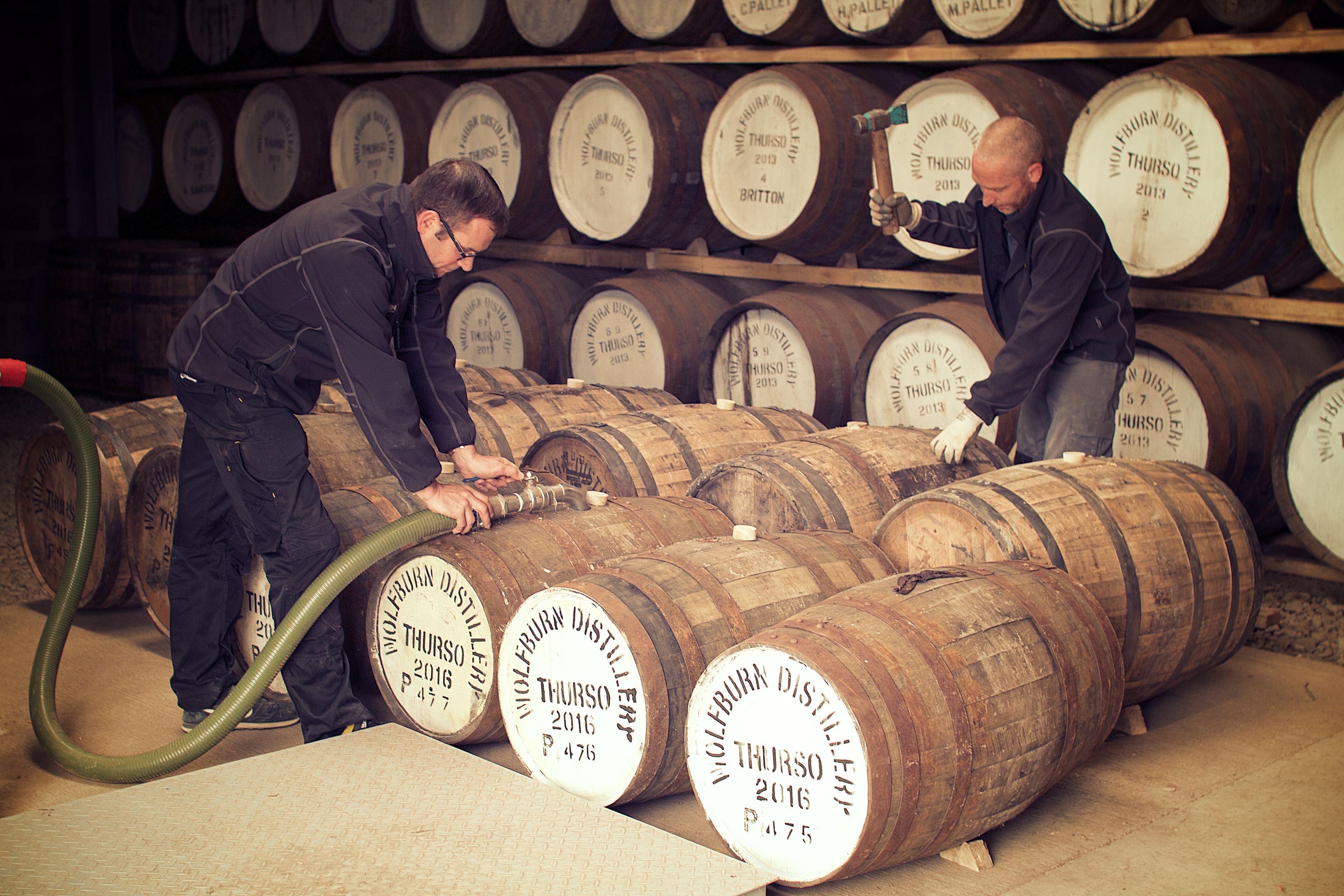 Shane Fraser and Iain Kerr filling casks at Wolfburn Distillery.