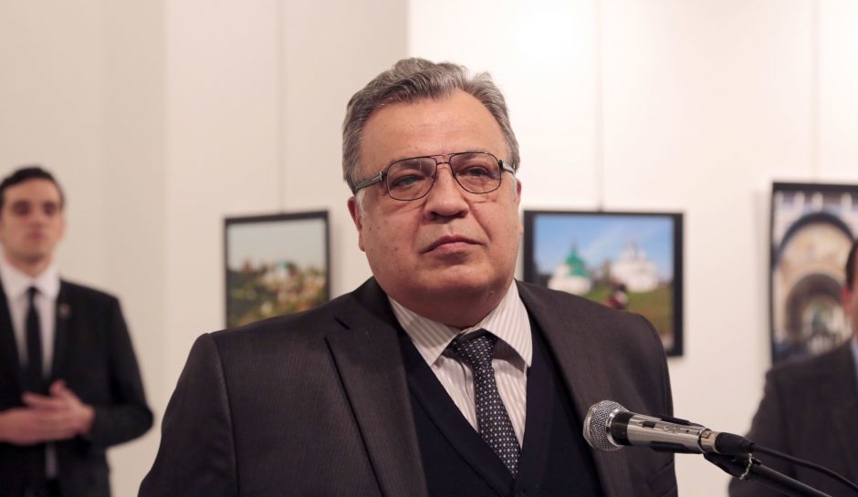 The Russian Ambassador to Turkey Andrei Karlov speaks a gallery in Ankara Monday Dec. 19, 2016. A gunman opened fire on Russia's ambassador to Turkey Karlov at a photo exhibition on Monday. The Russian foreign ministry spokeswoman said he was hospitalized with a gunshot wound. The gunman is seen at rear on the left.  (AP Photo/Burhan Ozbilici)