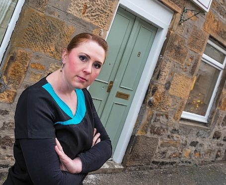 Claire Emson is the business owner outside her front door which was forced open.