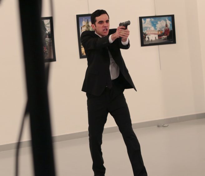 An unnamed gunman gestures after shooting the Russian Ambassador to Turkey, Andrei Karlov, at a photo gallery in Ankara, Turkey, Monday, Dec. 19, 2016. The Russian foreign ministry spokeswoman said he was hospitalized with a gunshot wound. (AP Photo/Burhan Ozbilici)