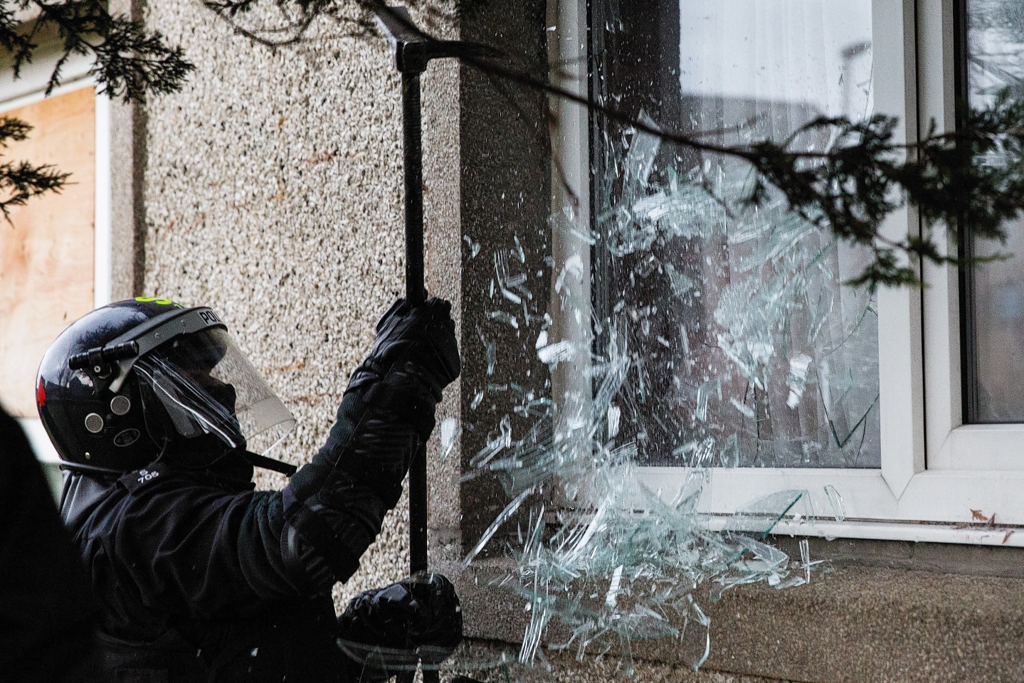 Police break a window to gain entry into a raided property.