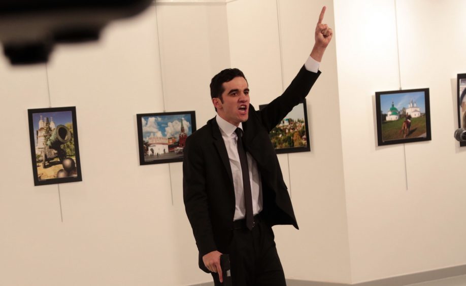 A man gestures near to the body of a man at a photo gallery in Ankara, Turkey, Monday, Dec. 19, 2016. An Associated Press photographer says a gunman has fired shots at the Russian ambassador to Turkey. The ambassador's condition wasn't immediately known. (AP Photo/Burhan Ozbilici)