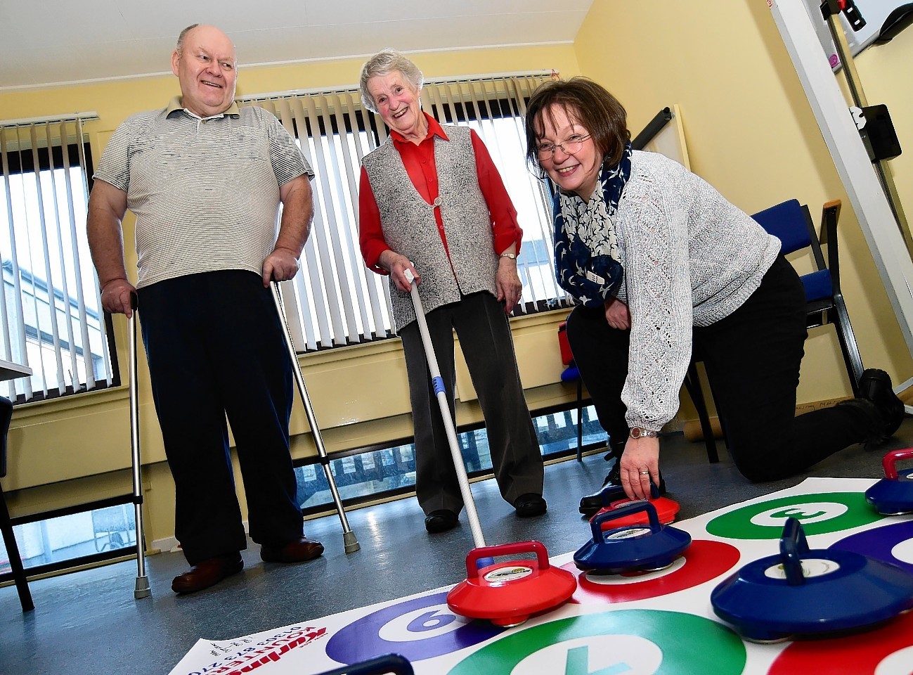 MEMBERS OF THE CHEST HEART AND STROKE SUPPORT GROUP PLAYING NEW AGE KURLING AT THEIR WEEKLY MEETING (L TO R) JOHN  NEISH, AGNES GAIRNS AND SUPPORT WORKER CAROLINE PETER.