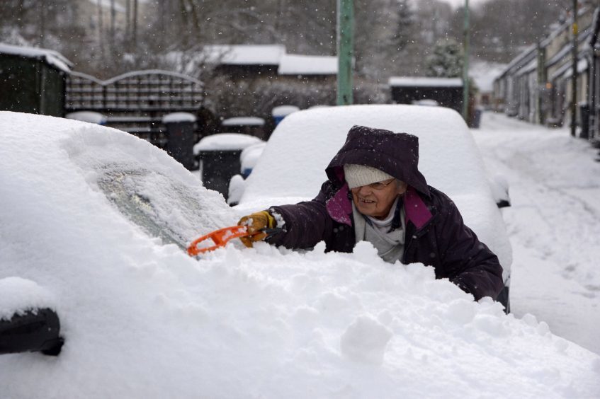 A women clears snow from a car in Leadhills, South Lanarkshire