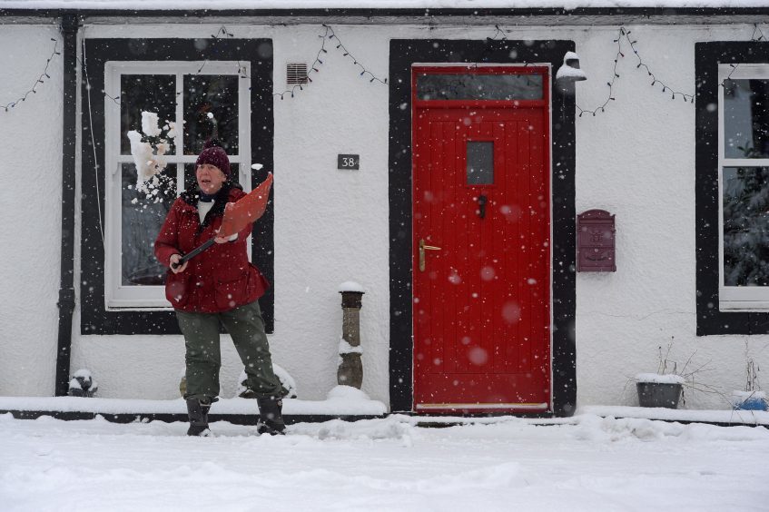 Jen Nicholls clears snow in front of her house in Leadhills, South Lanarkshire