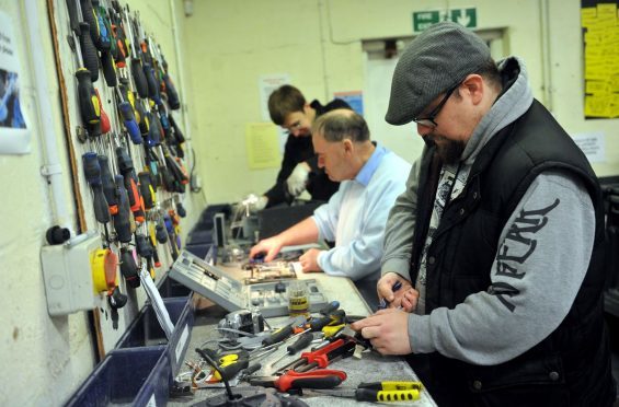 Volunteers at Reboot in Forres working on the bench - breaking computer equipment for scrap. Picture by Gordon  Lennox.