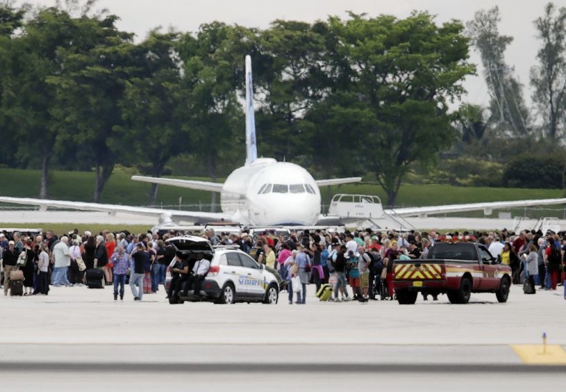 People stand on the tarmac at the Fort Lauderdale-Hollywood International Airport