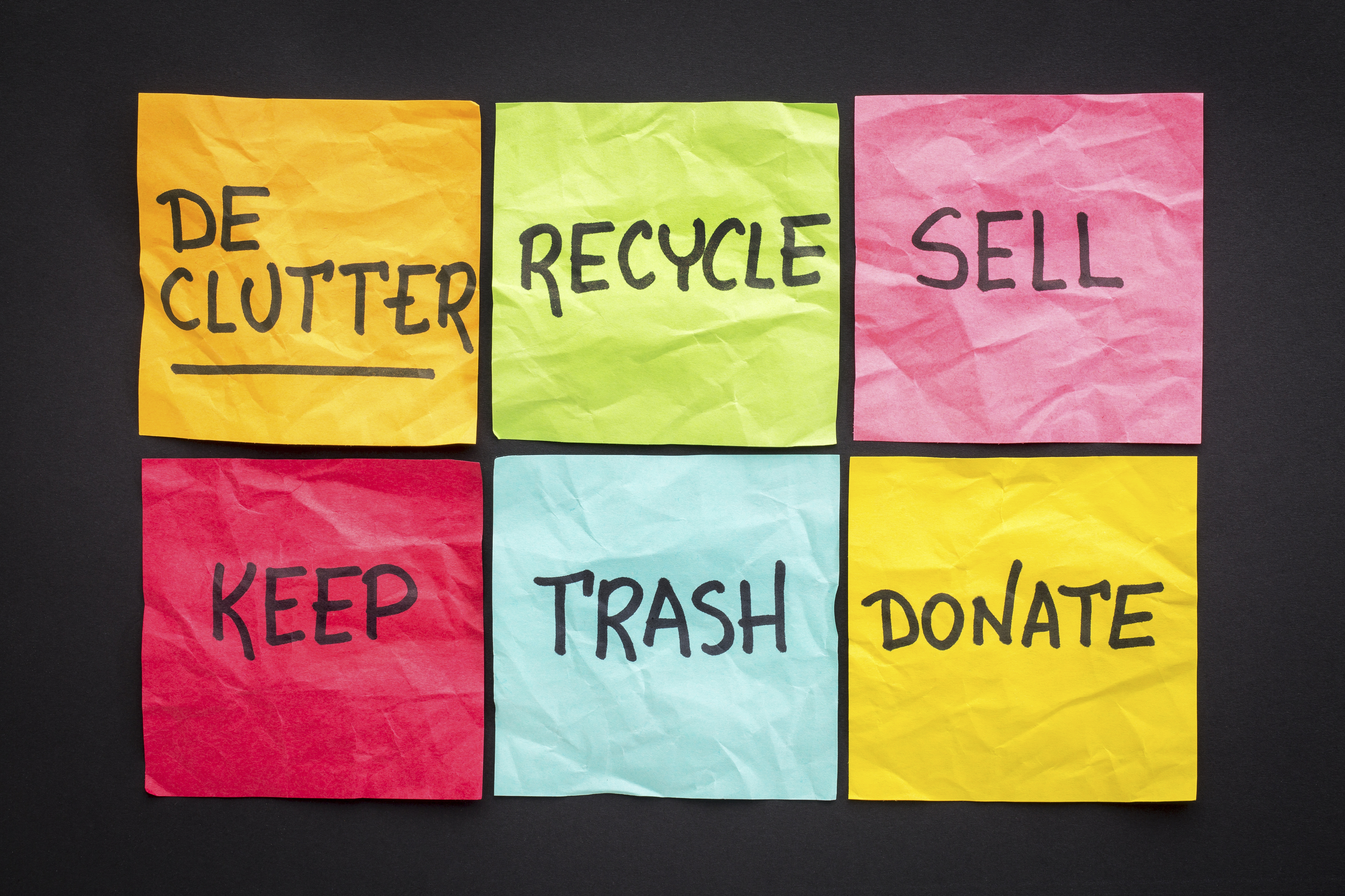 declutter concept (keep, recycle, trash, sell, donate - handwriting on color sticky notes against black paper background