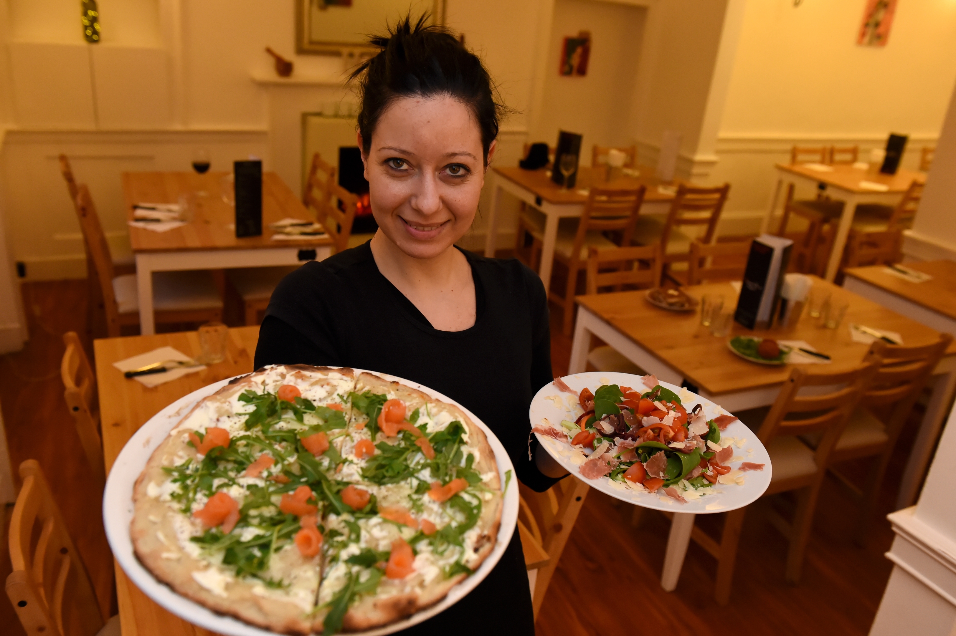Alessandra Di Carlo holding a pizza and salad. 