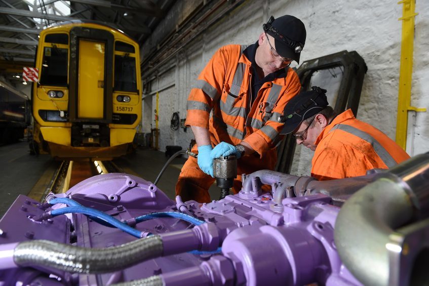 Fitters Andy Cooper and Rab Smith (right). New engine being fitted to a train unit.