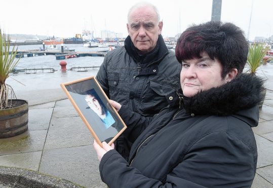 Hugh and June McLeod with a photograph of their late son Kevin at the scene in Wick Harbour  where the fatal incident took place.