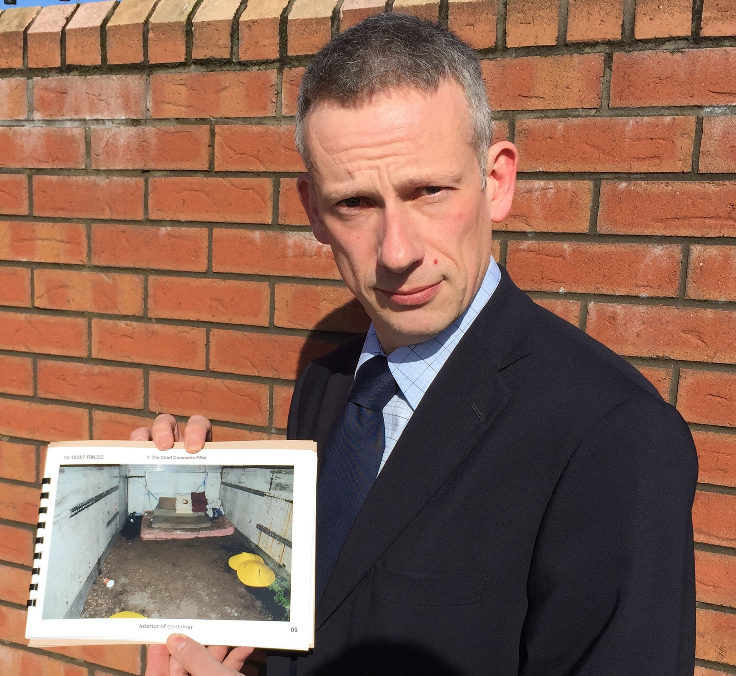 PSNI's Detective Chief Superintendent Raymond Murray holding a picture of squalid shipping container 