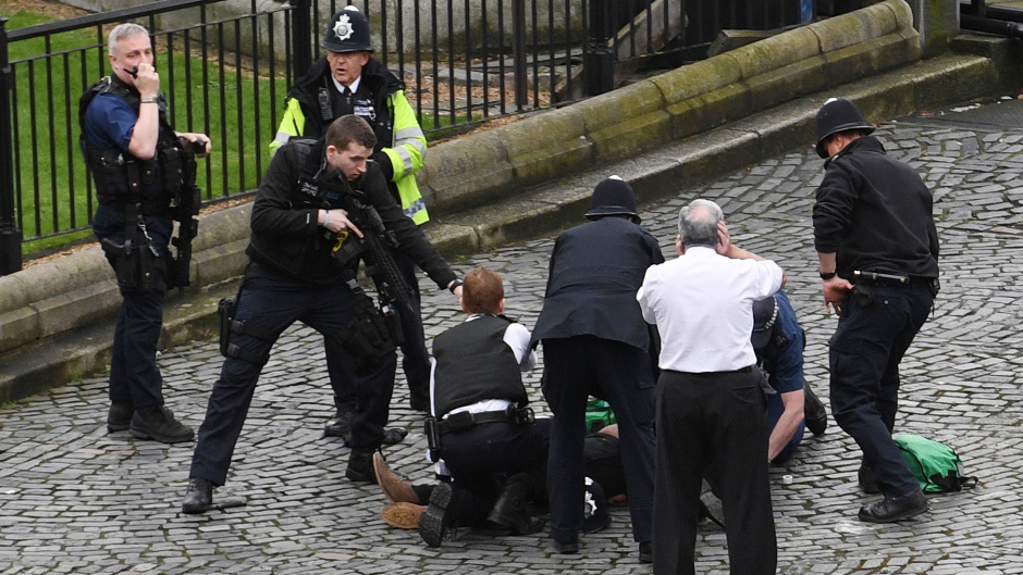 A policeman points his gun at the suspected attacker downed outside the Palace of Westminster
