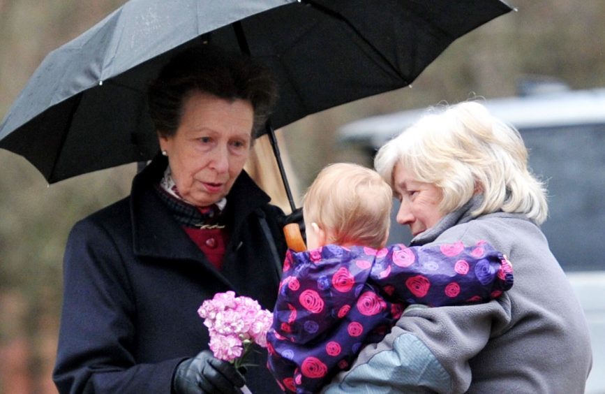 Princess Anne is greeted by one-year-old Isadora Sills at the entrance to St Christopher's Chapel at Gordonstoun.