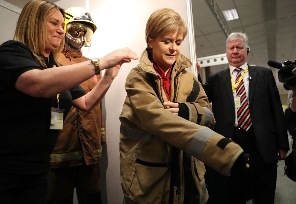 First Minister Nicola Sturgeon tries on a firefighters outfit as she tours the stalls at the SNP Spring Conference at the AECC in Aberdeen (Andrew Milligan/PA)