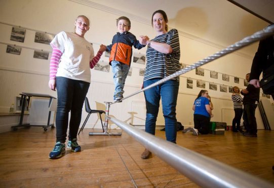 Callum Evans, 3, puts his balance to the test on the high wire with help from his mum Stephanie Evans, right, and workshop assistant Joanne Findlay.