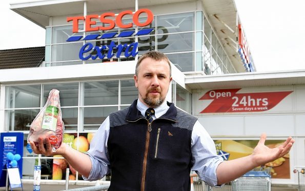 John Fyall holds a leg of New Zealand lamb outside the Tesco store in Aberdeen.